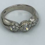 An 18ct white gold three stone diamond ring, remodelled by Grima of London. Central old cut diamond,