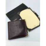 Pair of black leather note pads with rolled gold corners together with a maroon snake skin wallet by