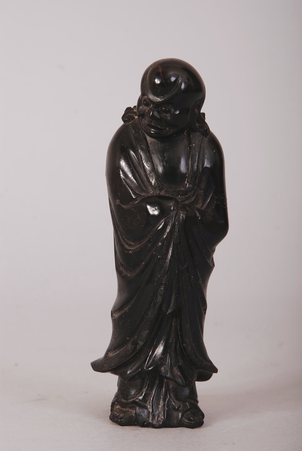 C18th/19th Chinese hardstone figure of Luohan, shown standing with his head turned slightly to the