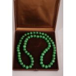 C20th Chinese emperor-green jade necklace composed of a strand of round even-sized beads, 85cm long,