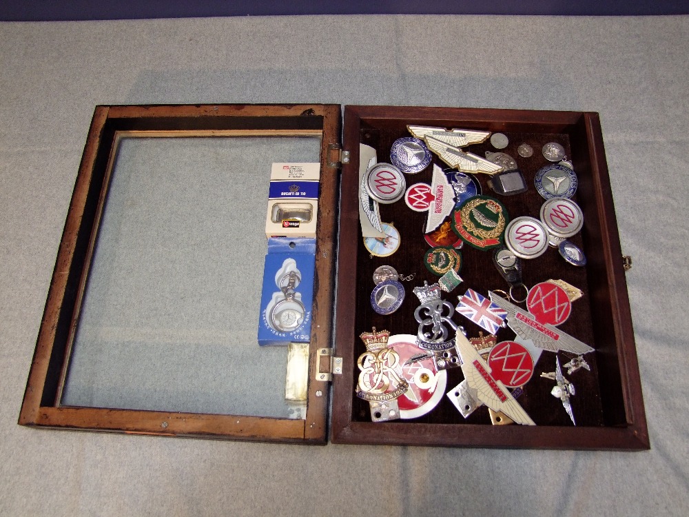 Table top display case containing Aston Martin & Mercedes Benz lapel badges, grille & bodywork