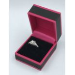 Ring 18ct white gold, central stone emerald cut, flanked by brillant cut diamonds