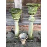 Pair of weathered composite urns on columns & small composite urn