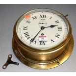 A circular brass cased ships clock, having white painted dial with Roman numerals,