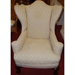 An early 20th century cream floral upholstered wingback armchair in the Queen Anne taste,