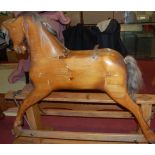 A Victorian style stained pine rocking horse raised on pine base with iron fittings,