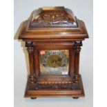 A late 19th century continental carved walnut cased mantel clock having a silvered dial with Arabic