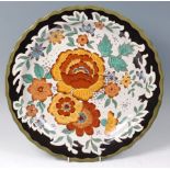 A Gouda pottery Unica charger, having a piecrust edge with painted floral stylised decoration,