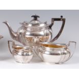 An Edwardian silver three piece tea-set, comprising teapot, twin handled sugar and cream jug,