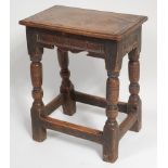 An 18th century joined oak stool, the top having a moulded edge over a shaped frieze,