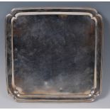 A George V silver serving tray, of shaped square form within raised border,