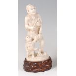 A Japanese Meiji period (1868-1912) carved ivory okimono, modelled as a street-vendor with child,