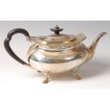 A George V silver teapot, of squat oval form, having shaped rim and ebonised handle,