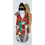 A Japanese stoneware and enamel decorated figure of a geisha girl in standing pose with kitten at