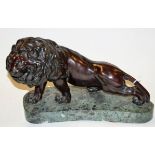 A bronze figure of a lion in stalking pose on a green variegated marble plinth,