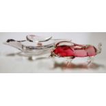 A pink tinted and clear glass model of a bull in fighting pose together with a clear glass table