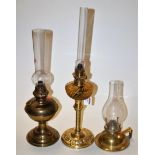 An early 20th century brass pedestal oil lamp having a smoky glass reservoir together with two