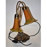 An Art Nouveau style table lamp having yellow/green tinted glass shades to brass lily pad base,