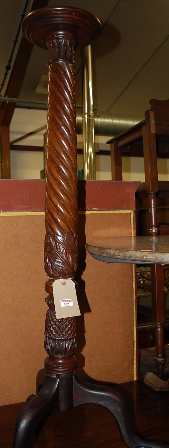 An early 20th century mahogany plant stand, the column floral carved and of spiral reeded form,