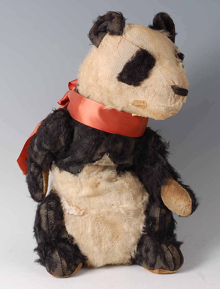 An early 20th century straw filled and mohair childs panda bear, with orange silk collar,