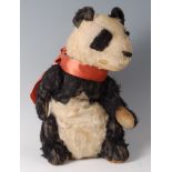 An early 20th century straw filled and mohair childs panda bear, with orange silk collar,