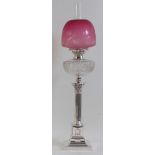 A circa 1900 silver plated Corinthian column pedestal oil lamp, having cranberry tinted dome shade,