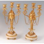 A pair of circa 1900 gilt bronze and white marble three-light candelabra, in the Louis XVI style,