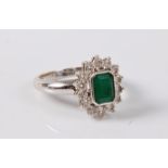 An emerald and diamond cluster ring, the emerald cut emerald in a rubover mount,