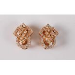 A pair of diamond earclips, the stylised geometric open flowers set with small round diamonds,