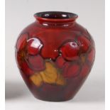 An early 20th century Moorcroft pottery squat vase in the Flambé Clematis pattern,