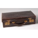 An early 20th century crocodile skin travelling case, having gilt brass twin lock fittings,