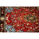 A Persian woollen Mashad red ground rug,