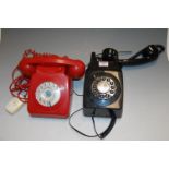 A black plastic wall mounted telephone together with one other red plastic example (2)