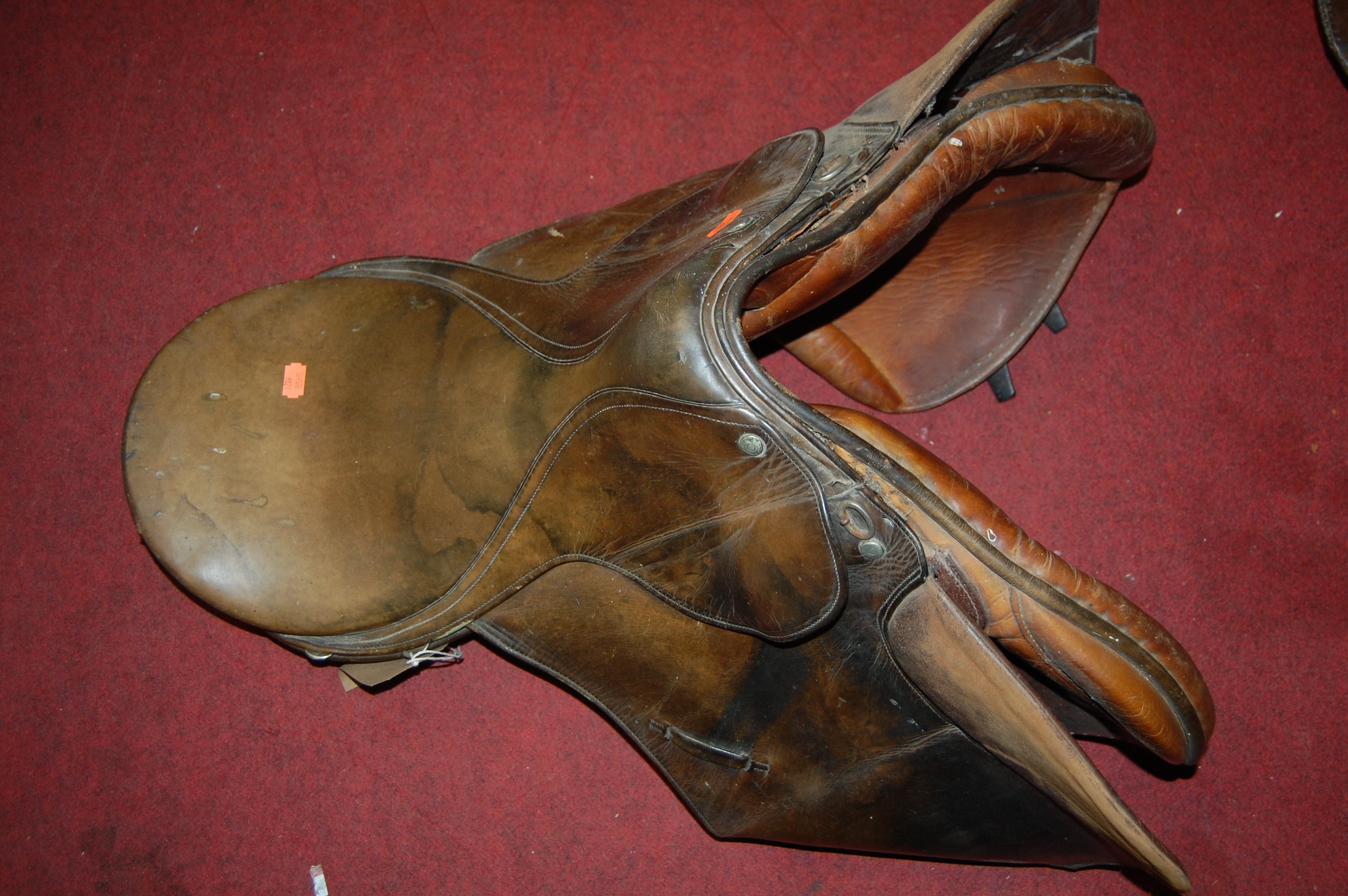 Two brown leather horse riding saddles
