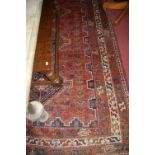 A Persian woollen red ground rug having geometric lozenge central decoration, 254x178cm