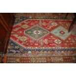 A Persian red ground woollen rug with multiple trailing borders, 250x150cm