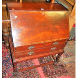 An early 20th century walnut slopefront writing bureau, having two short over single long drawer, on