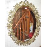 A gilt brass bevelled oval wall mirror, the frame of pierced floral design, h.84cm