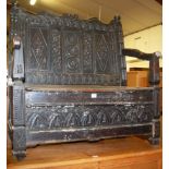 An antique ebonised and relief carved oak two seater box seat settle (requires restoration), width