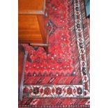 A Persian woollen red ground rug, having multiple trailing borders, 300 x 215cm