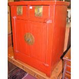 A Chinese red lacquered double door side cupboard having twin upper drawers, width 65cm