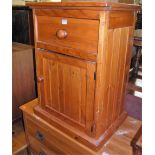 A stained pine single door bedside cupboard having single upper drawer, width 53cm