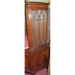 A reproduction mahogany bowfront corner cupboard, having glazed upper door