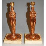 A pair of copper figural candlesticks, each on a marble plinth, h.26cm