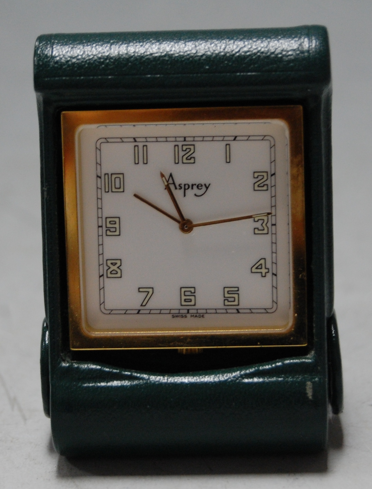 A small gilt metal cased travel clock in green leather outer case by Asprey