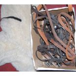 A sheepskin numnah together with various bridle tack, three brown leather saddles