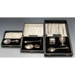 A cased silver three-piece christening set, comprising eggcup, napkin ring, and egg spoon; and two