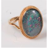 A 9ct opal ring, the oval opal, possibly a doublet, collet mounted with rope twist border, split