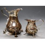 An Edwardian silver cream jug, on hoof feet (a/f); together with one other smaller embossed example,