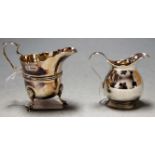 A George V silver cream jug on hoofed feet together with one other silver cream jug (2)